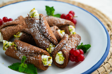 Sicilian cannoli filled with ricotta cheese cream and topped with chopped pistachios.