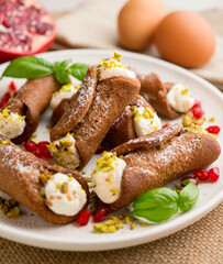 Sicilian cannoli filled with ricotta cheese cream and topped with chopped pistachios.