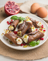 Sicilian cannoli filled with ricotta cheese cream and topped with chopped pistachios.