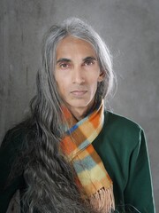 Portrait of a long haired man with light skin tone wearing flannel scarf