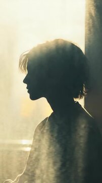A silhouette of a person standing in front of a window