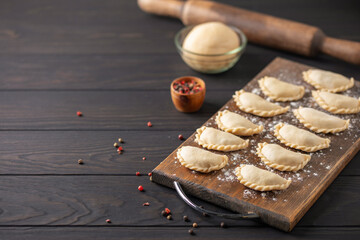 Homemade uncooked russian dumplings pelmeni on wooden board.