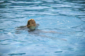 Obraz premium Young girl enjoying swimming in a clear blue pool during summer vacation