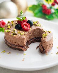 Chocolate mousse tart filled with jam and decorated with pistachios and red berries.