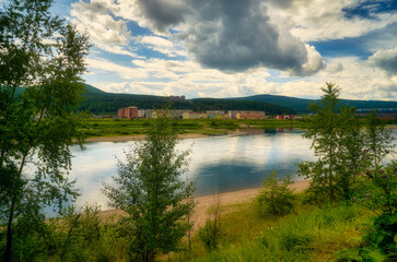 The Siberian Lena River flows within the city limits, surrounded by forested hills, residential high-rise buildings stand closer to the shore, and harsh Siberian nature