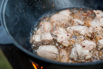 Cooking recipe for cooking meat in a cast-iron cauldron outdoors. Cooking food. Frying meat.