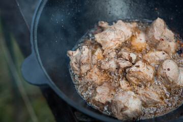 Cooking recipe for cooking meat in a cast-iron cauldron outdoors. Cooking food. Frying meat.