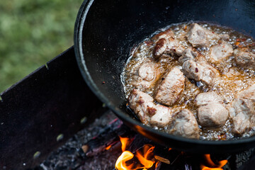 Cooking recipe for cooking meat in a cast-iron cauldron outdoors. Cooking food. Frying meat.