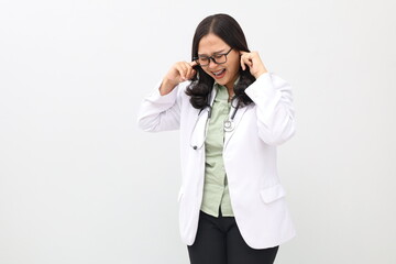 Pretty adult doctor man wearing doctor's suit over isolated background covering ears with fingers with annoyed expression for the noise of loud music. Deaf concept.