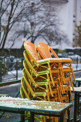 Chairs covered with snow in a restaurant in Paris, France.