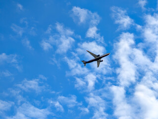 An airplane against a blue sky with white clouds