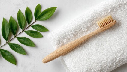 Eco friendly bamboo toothbrush on a white towel with a green plant branch.