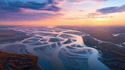 Aerial view of a winding river delta at sunset with dramatic clouds and calm water reflecting the skys vibrant colors