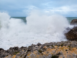 Big ocean wave crashing on asturias rocky coast