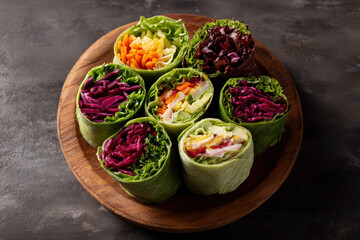 Assorted healthy wraps with vibrant vegetables on wooden platter