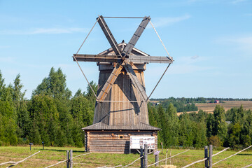 Obraz premium Historic Wooden Windmill with Large Blades under Blue Sky
