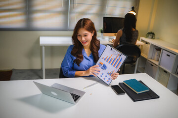 Asian businesswoman showing financial charts during video call, having online business meeting in modern office