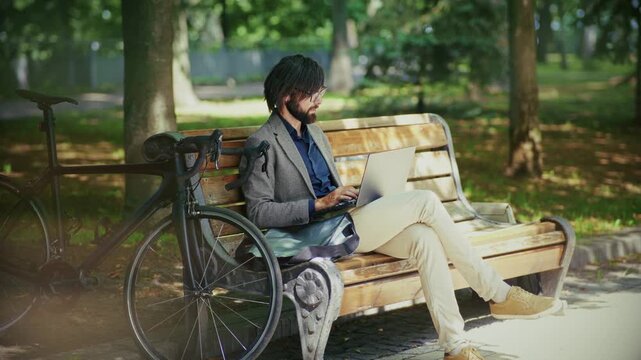 Man sitting bench with computer overtime working outdoor	