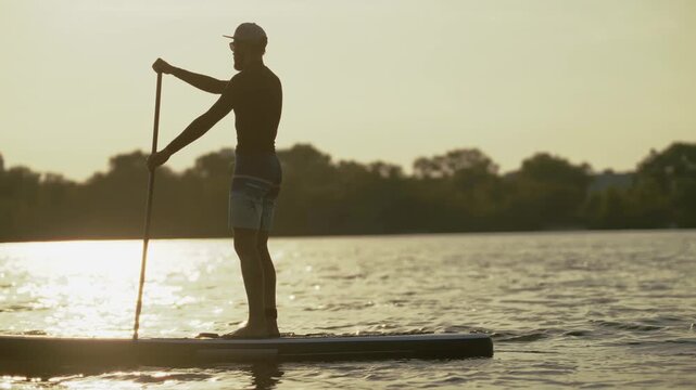 Active man paddle boarding on lake surrounded by nature	