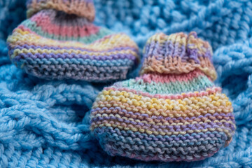 hand knit baby booties, knitting on a knit blanket 