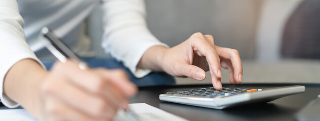 Women business people use calculators to calculate the company budget and income reports on the desk in the office.