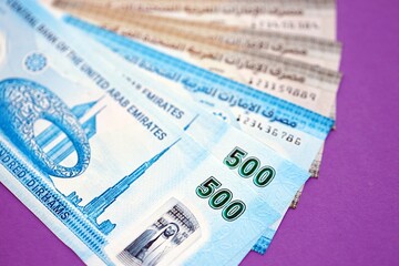 Obraz premium United Arab Emirates dirham money bills in big amount close up on purple. Finance and banking concept