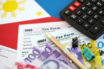 Philippines peso money bills and calculator with tax form on flag close up. Taxation and accounting...
