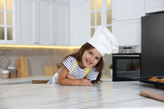 Choice of profession. Little girl pretending to be chef at table in kitchen