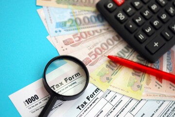 Vietnamese dong money bills and calculator with tax form close up on blue. Taxation and accounting...