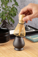 Hand is using a bamboo whisk to make Japanese  matcha tea ceremony.
