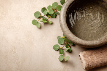 Stone basin with rippling water and eucalyptus leaves on a neutral spa surface. AI generative