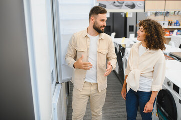 Fototapeta premium Couple choosing refrigerator in home appliance store