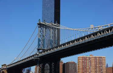 manhattan bridge viewed from under and behind modern skyscraper in new york usa