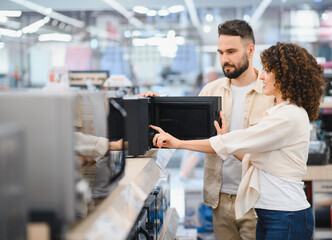 Couple choosing microwave oven in electronics store