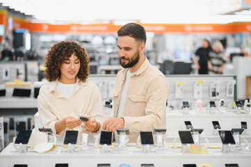 Couple exploring smartphones in electronics store