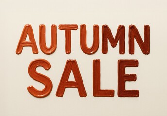 Autumn sale lettering made with glossy brown cosmetic smear on beige background. Creative beauty concept for makeup promotions and holiday discounts.	