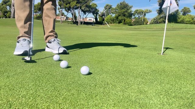 A man is playing golf and has just hit a ball. The ball is in the air and is heading towards the hole