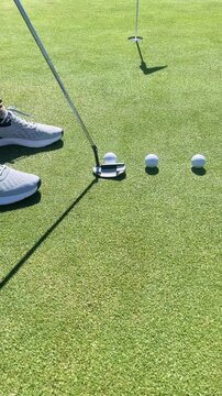 A golf course with three golf balls on the grass. The balls are in a row and are in the foreground