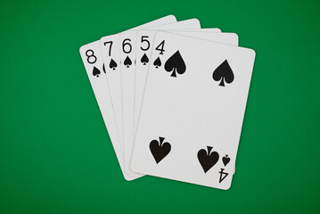 Playing cards showing straight flush poker hand on a green background, symbolizing gambling, poker, and the risks of casino games.