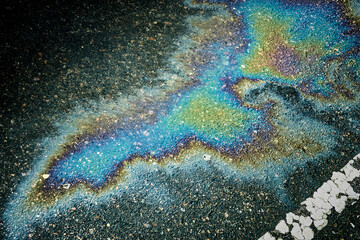Oil spill rainbow iridescent pattern on asphalt road