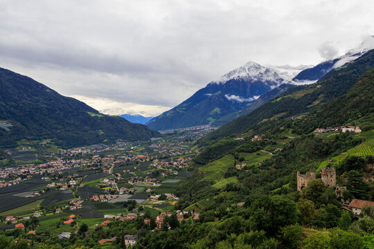 Panorama with castle Schloss Brunnenburg, snowcapped mountain summit Cima di Tel (Zielspitze) and valley Etschtal seen from Tirol (Dorf Tirol) on a cloudy day in autumn in South Tyrol, Italy