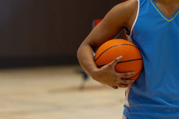 African American male holding orange basketball wearing blue jersey on gym court, copy space