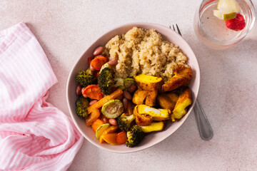 A nutritious breakfast showcases a bowl of quinoa accompanied by vibrant baked sweet potatoes, carrots, zucchini, beans, and turmeric chicken, paired with a fresh salad on the side