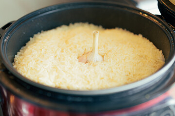 cooked rice with a whole garlic head in a black pot. a cozy and mouth-watering close-up, capturing the simple beauty of a home-cooked meal
