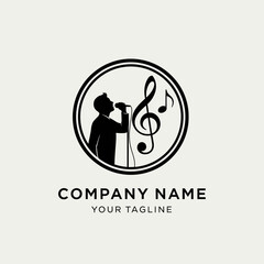 A black and white circular logo featuring a silhouette of a person singing into a microphone, accompanied by musical notes and a treble clef.