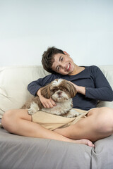 Smiling 12 year old Brazilian teenager on the sofa next to his dog_vertical.