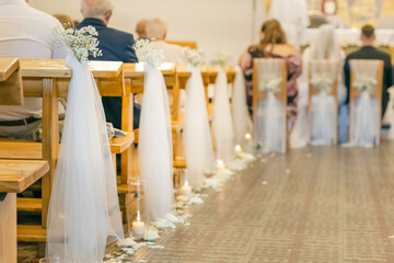 White tulle ribbon tied to wooden pew as wedding church decoration