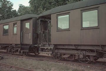 Historic wooden train carriages connected together on old railway tracks in a vintage railway station setting