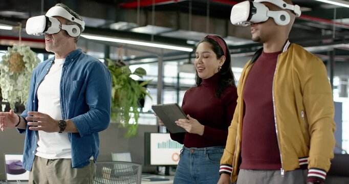 Diverse coworkers tapping tablet in office to launch VR demo, wearing headsets and collecting data