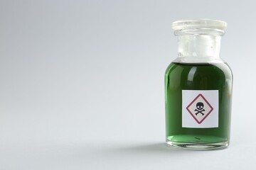 Bottle of poison with warning sign on light background. Space for text